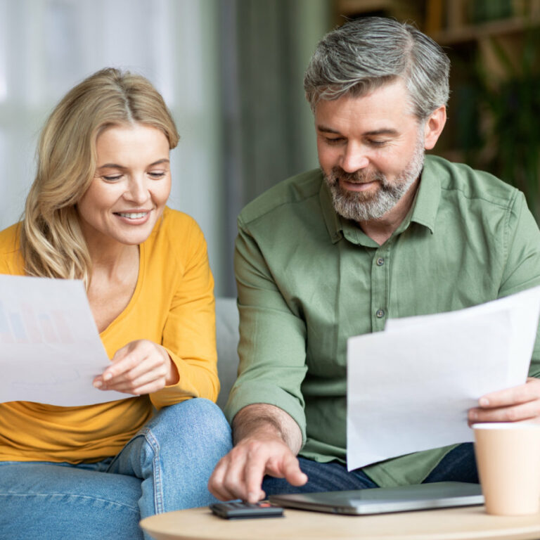 Middle aged spouses checking financial documentation while planning family budget at home